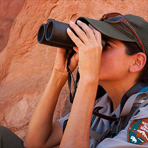 A park ranger looking through binoculars.